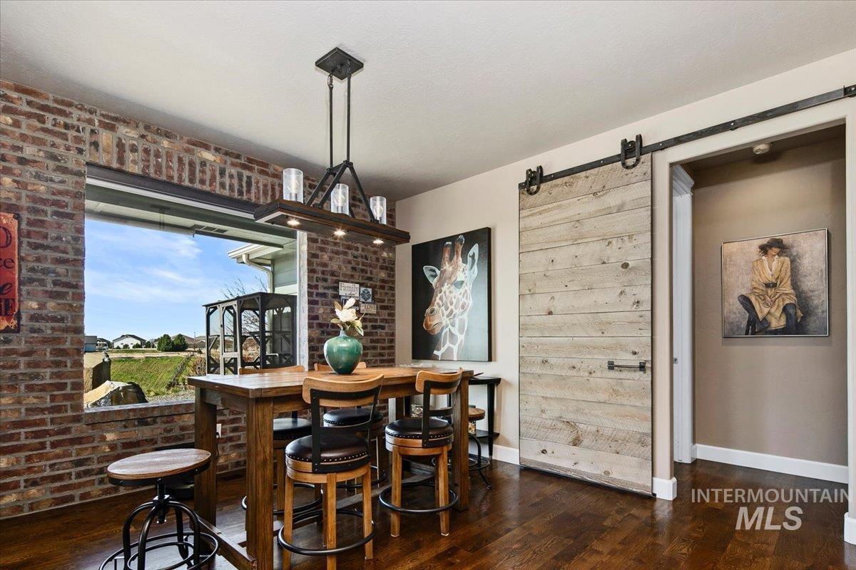 24053 Pheasant Ridge Court Middleton, ID 83644 - Photo 11 of 50 Dining room featuring a barn door, dark wood finished floors, and brick wall