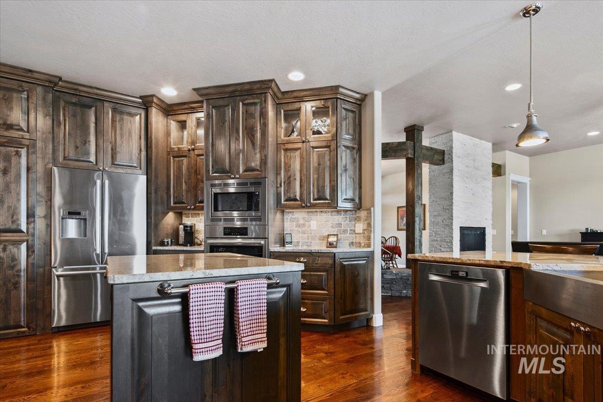 24053 Pheasant Ridge Court Middleton, ID 83644 - Photo 29 of 50 Kitchen featuring dark wood finish cabinets, stainless steel appliances, dark wood-style flooring, glass fronted cabinets, and a textured ceiling