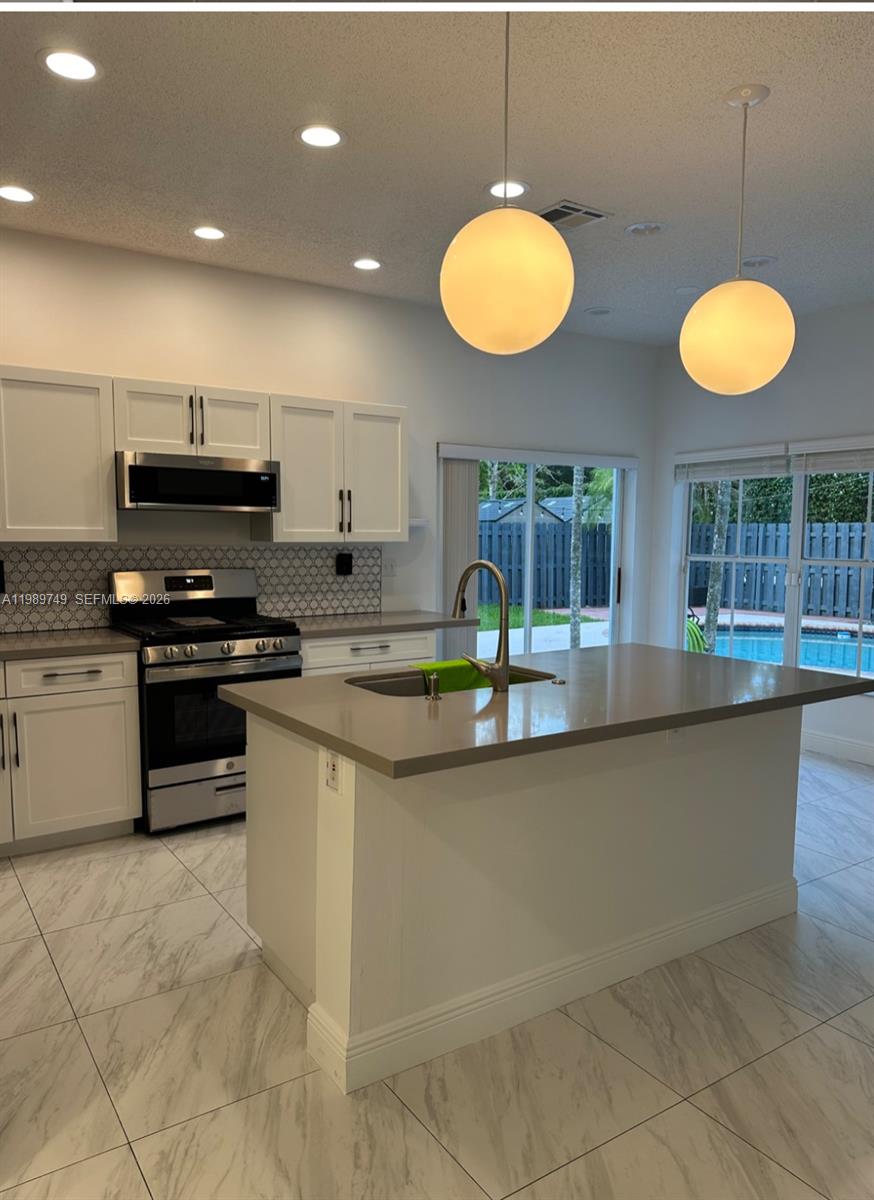 4021 Southwest 153rd Avenue Miramar, FL 33027 - Photo 2 of 42 a kitchen with stainless steel appliances granite countertop a stove a sink and a microwave