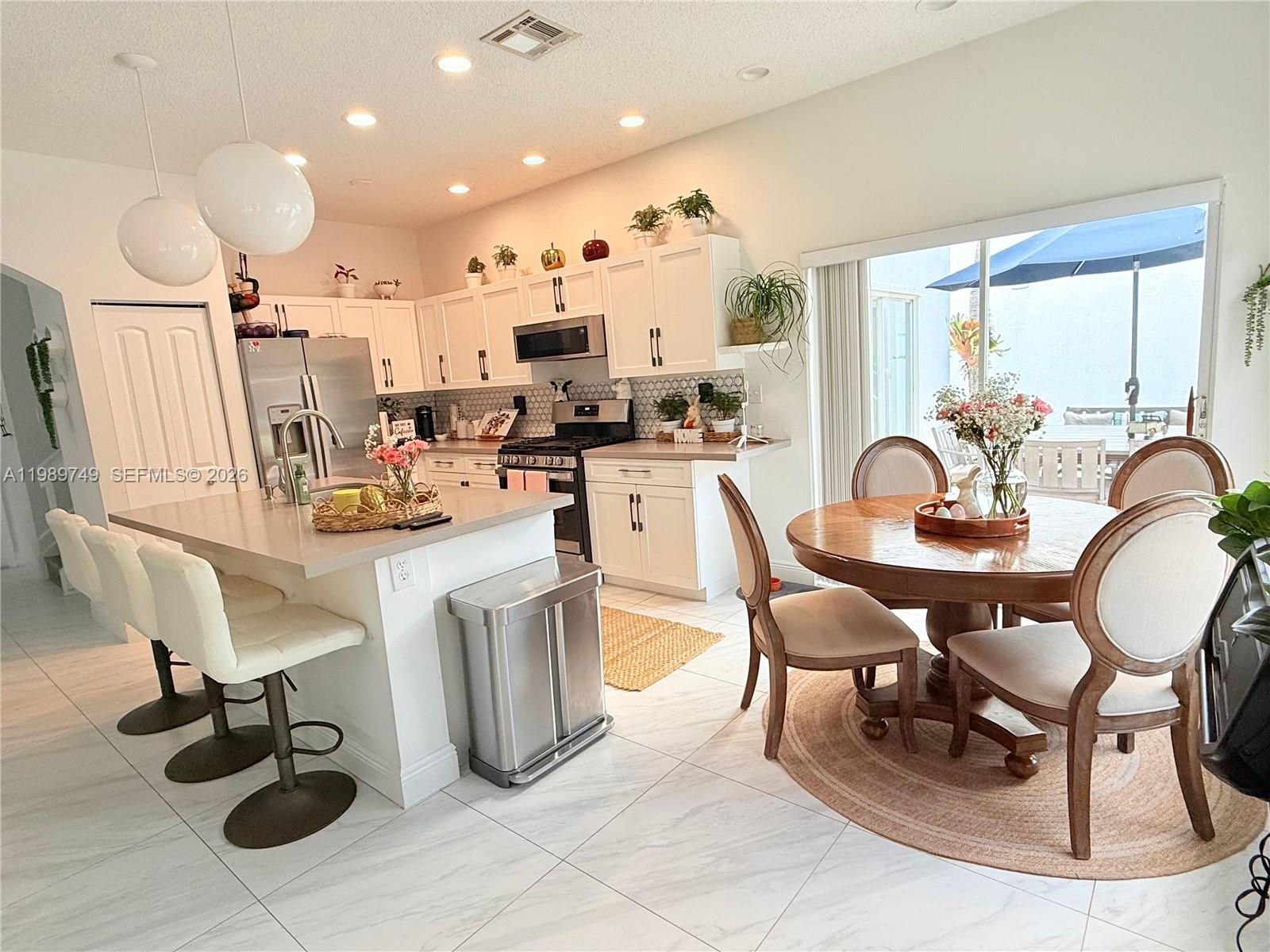 4021 Southwest 153rd Avenue Miramar, FL 33027 - Photo 26 of 42 a kitchen with kitchen island granite countertop lots of white furniture a sink a dining table and chairs