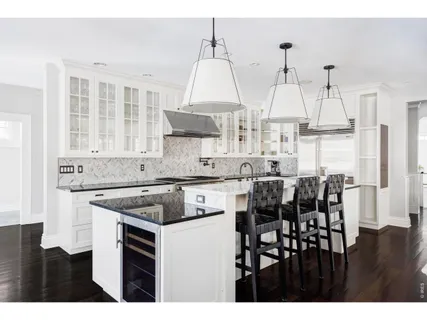 a kitchen with stainless steel appliances granite countertop a stove a sink dishwasher and white cabinets with wooden floor