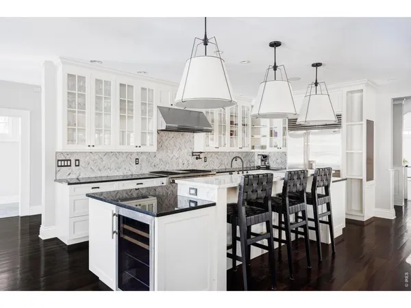 a kitchen with stainless steel appliances granite countertop a stove a sink dishwasher and white cabinets with wooden floor