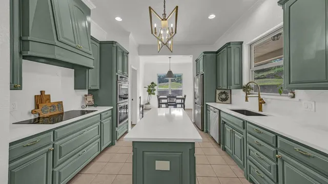 a kitchen with stainless steel appliances granite countertop a sink a stove top oven a chimney cabinets and a refrigerator