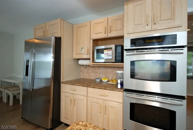 a kitchen with cabinets stainless steel appliances and wooden floor