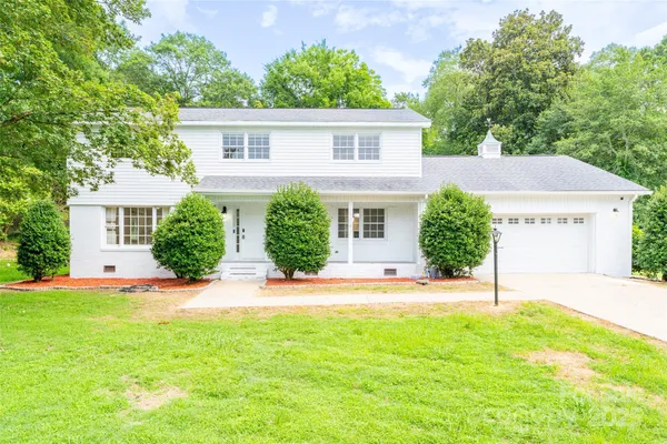 front view of a house with a yard and an trees