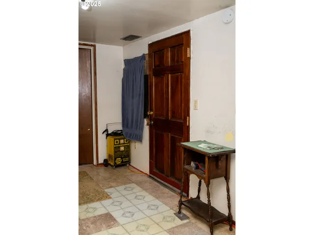 a view of hallway with a chair and frames on wall