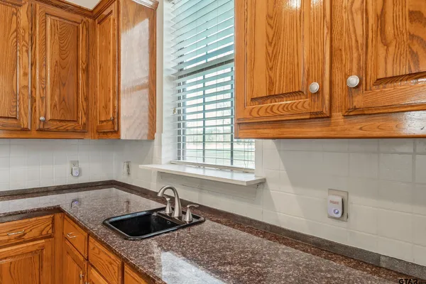 a kitchen with granite countertop a sink and a white cabinets