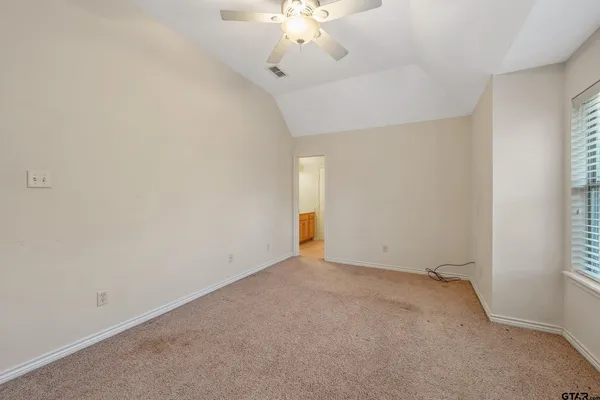 an empty room with a chandelier fan and windows