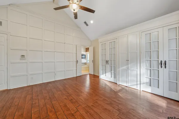 an empty room with wooden floor fan and windows