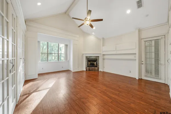an empty room with wooden floor fireplace and windows