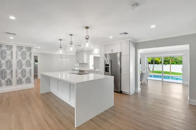 a large kitchen with stainless steel appliances a large counter top a sink a refrigerator and a window