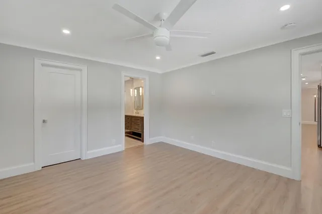 an empty room with wooden floor and ceiling fan