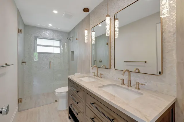 a bathroom with a granite countertop sink a toilet a mirror and shower