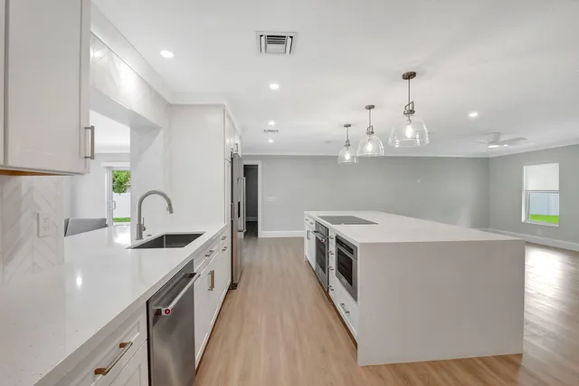 a kitchen with kitchen island a sink appliances and cabinets