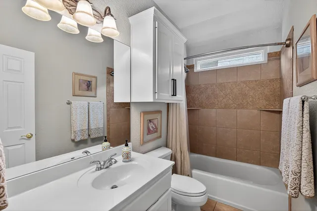 a bathroom with a sink a toilet a mirror a bathtub and shower