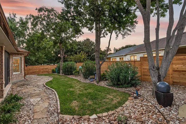 a view of a backyard with potted plants and large trees