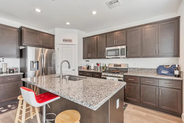 a kitchen with stainless steel appliances granite countertop a stove top oven a sink dishwasher and cabinets with wooden floor