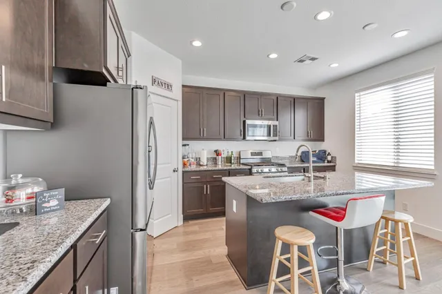 a kitchen with stainless steel appliances granite countertop a sink stove and refrigerator