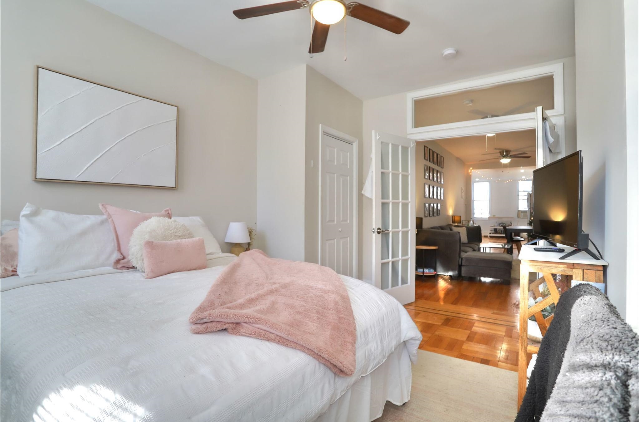 402 Monroe Street, Unit 2 Hoboken, NJ 07030 - Photo 15 of 22 a bedroom with a large bed and a flat tv screen on a dresser