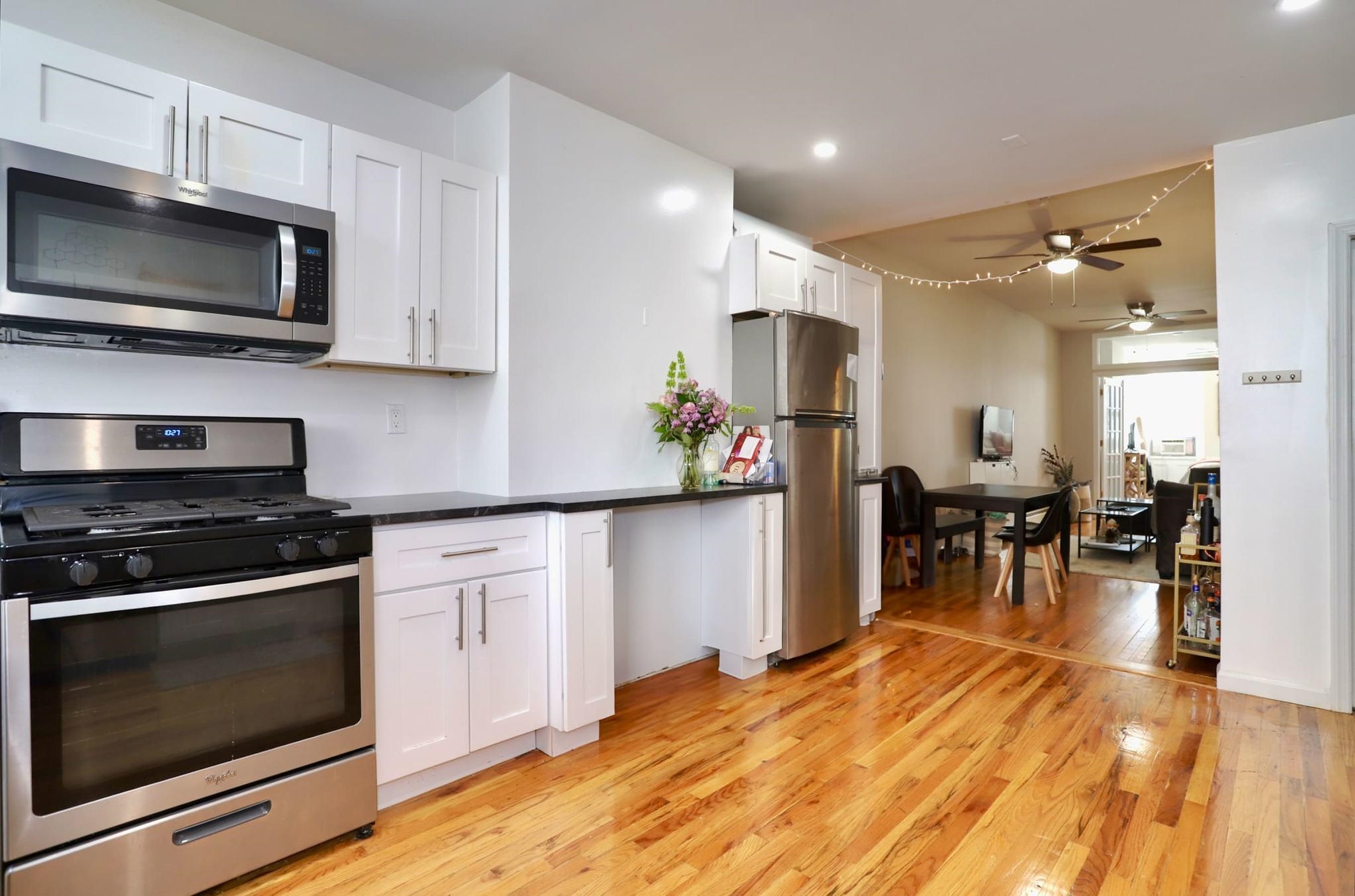 402 Monroe Street, Unit 2 Hoboken, NJ 07030 - Photo 4 of 22 a kitchen with stainless steel appliances kitchen island granite countertop a stove top oven a sink a dining table and chairs with wooden floor