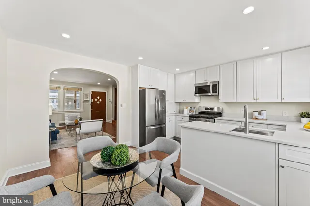 a kitchen with stainless steel appliances a dining table chairs sink and cabinets