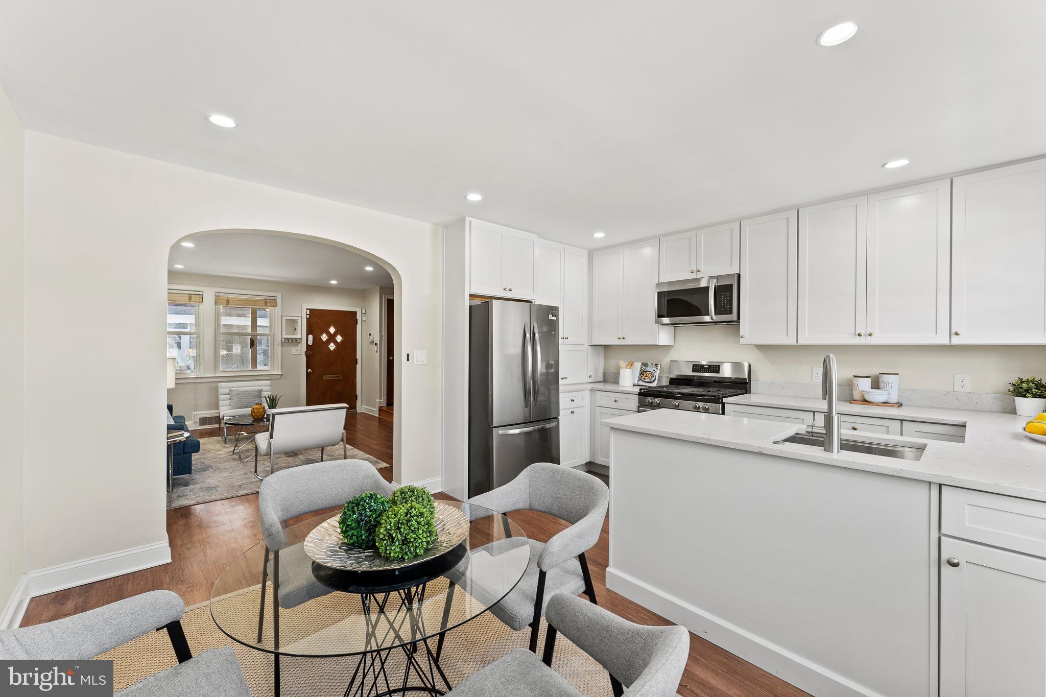 a kitchen with stainless steel appliances a dining table chairs sink and cabinets