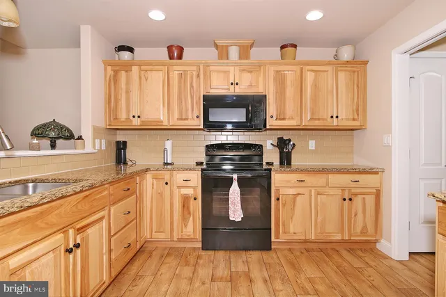 a kitchen with stainless steel appliances kitchen island granite countertop a stove top oven a sink dishwasher a dining table and chairs with wooden floor