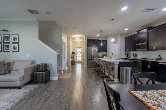 a living room with furniture kitchen view and a wooden floor