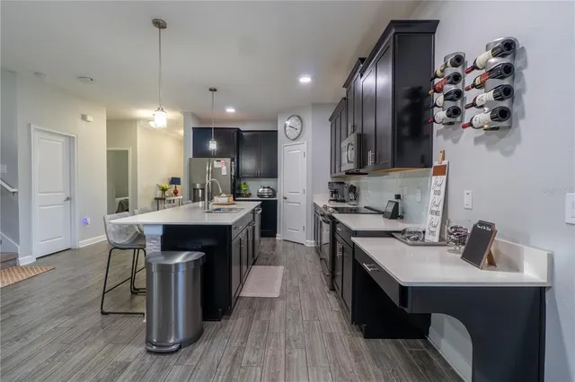 a kitchen with stainless steel appliances kitchen island granite countertop a table chairs sink and cabinets