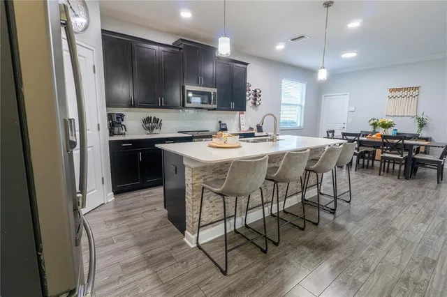 a kitchen with stainless steel appliances granite countertop a table chairs microwave and sink