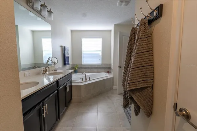 a spacious bathroom with a tub sink and mirror