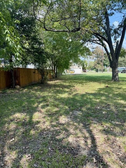 701 North Neal Street Commerce, TX 75428 - Photo 5 of 6 a view of backyard with large trees and wooden fence