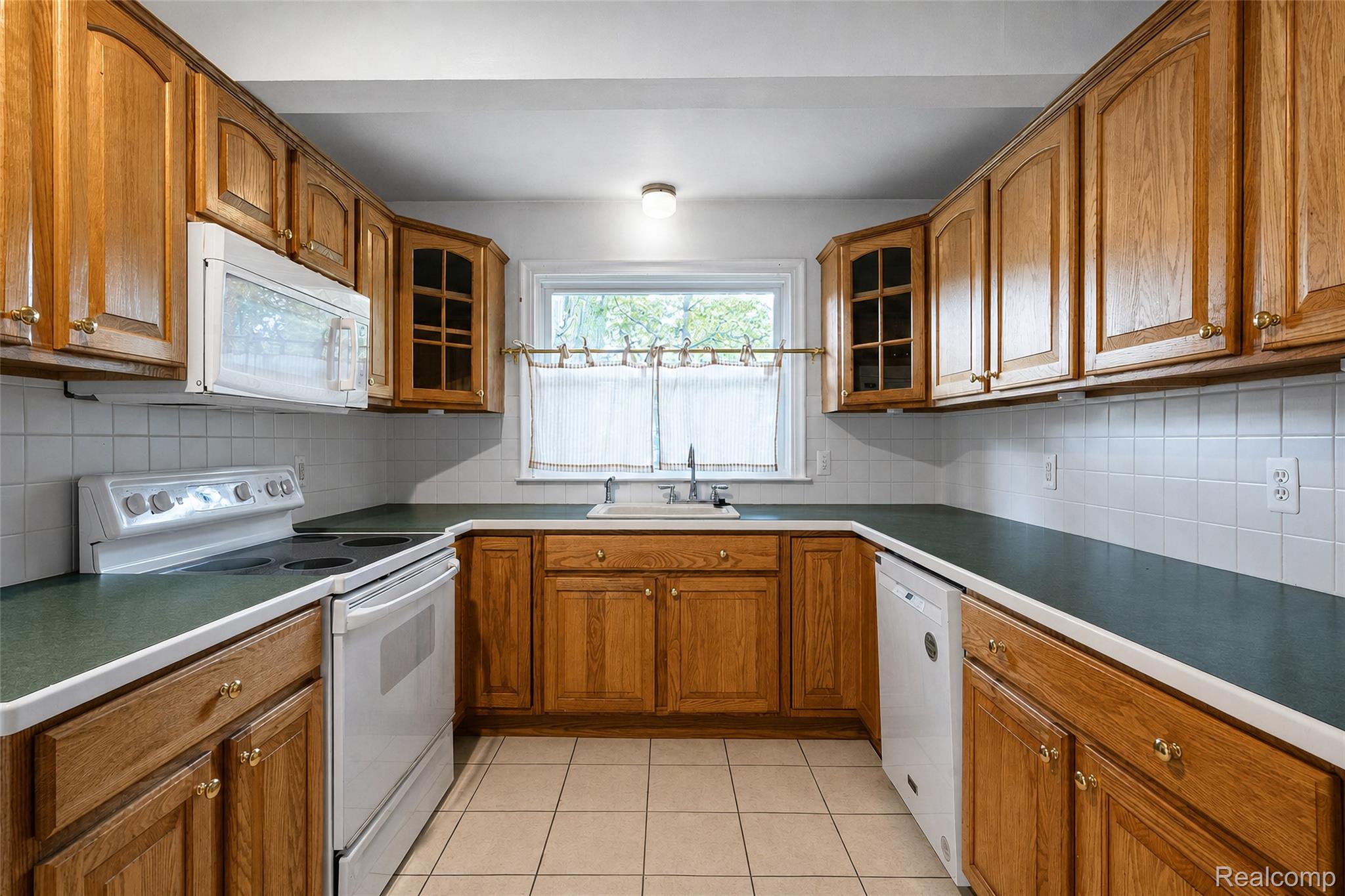 1846 Pembroke Road Birmingham, MI 48009 - Photo 23 of 37 U-shaped kitchen featuring wood cabinetry, white tile backsplash, a window above the sink, and built-in appliances
