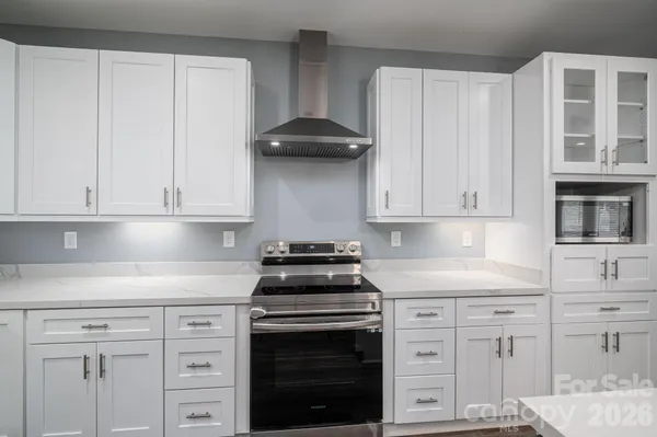 a kitchen that has a lot of white cabinets and a wooden floor