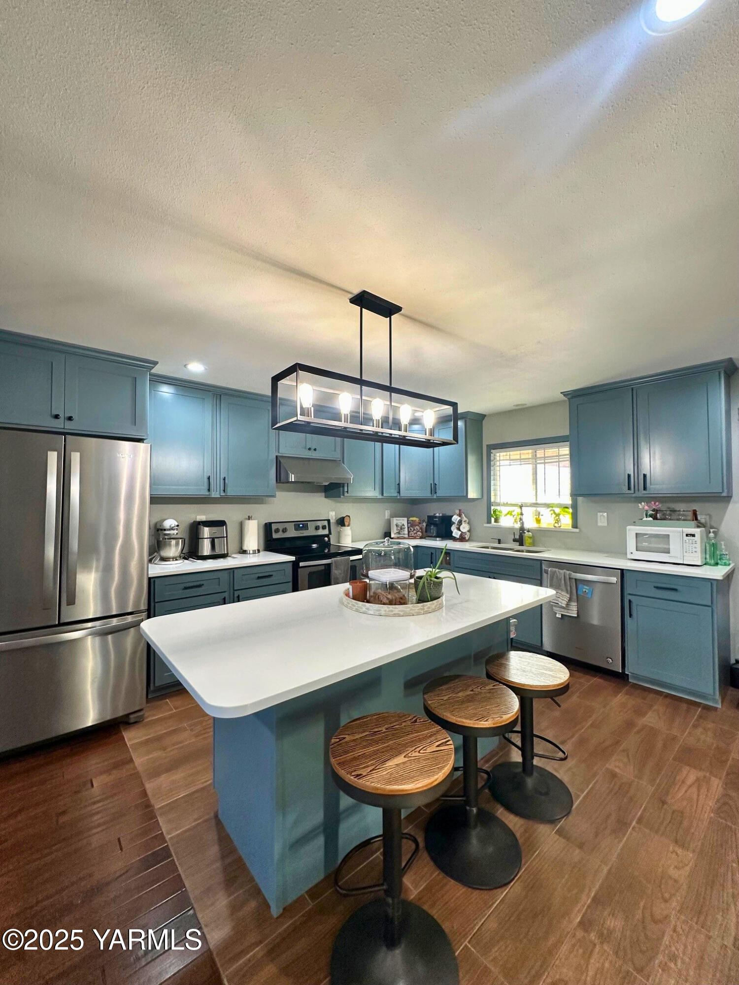 a kitchen with sink a refrigerator and chairs