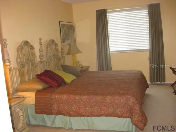 a bedroom with a bed and a dresser next to a window