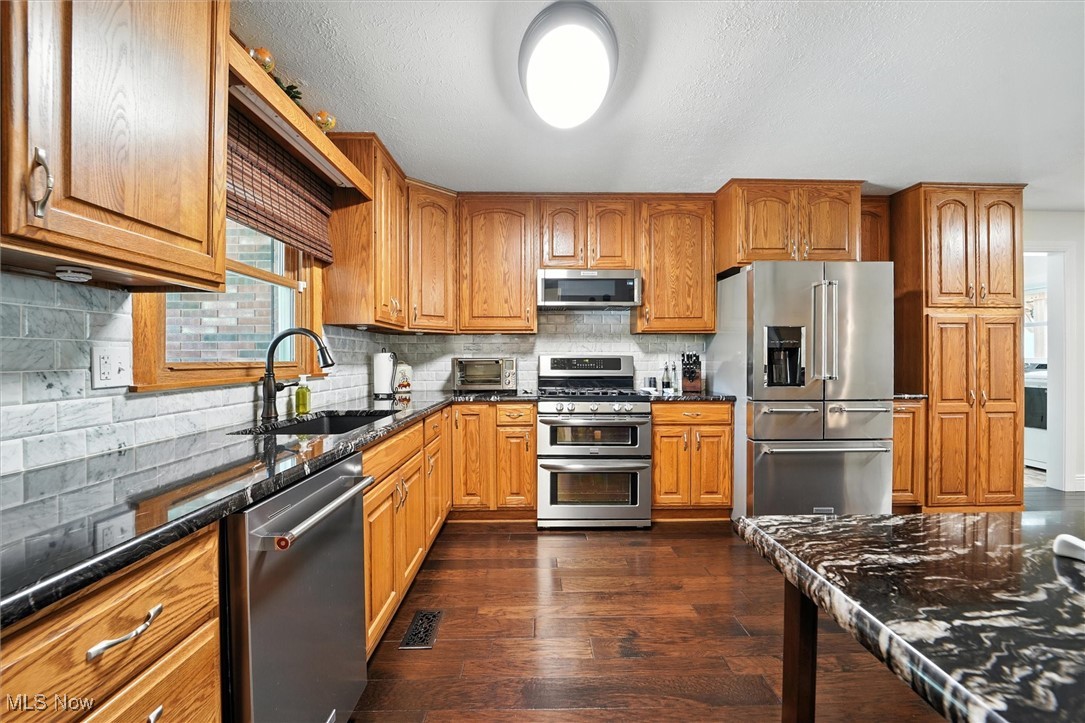 2930 South Ridge Road East Kingsville, OH 44048 - Photo 6 of 49 Kitchen with stainless steel appliances, dark wood-style floors, brown cabinetry, dark stone countertops