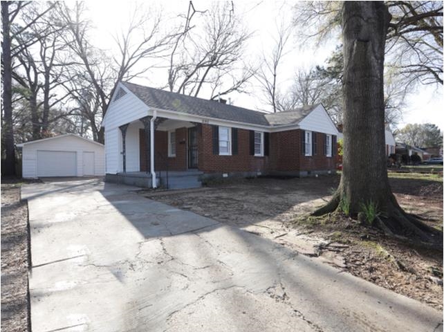 1180 Russwood Road Memphis, TN 38122 - Photo 3 of 5 Brick exterior with white gables and dark shutters, concrete driveway, detached two-car garage, covered front porch, mature tree