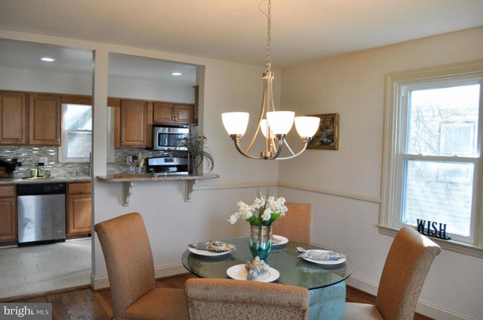 15 Summerfield Road Baltimore, MD 21207 - Photo 5 of 16 a kitchen with stainless steel appliances granite countertop a dining table chairs and a refrigerator