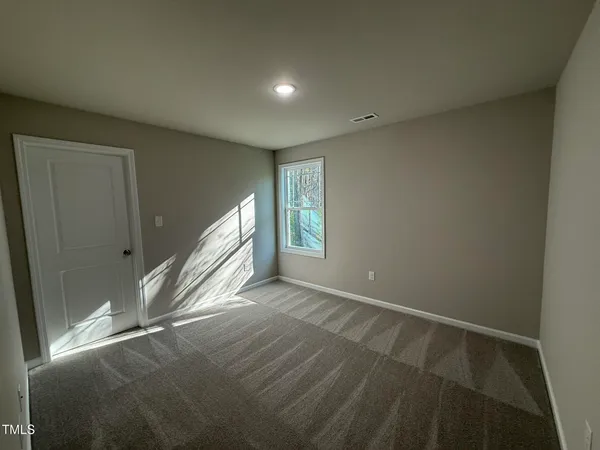 a view of an empty room with window and stairs