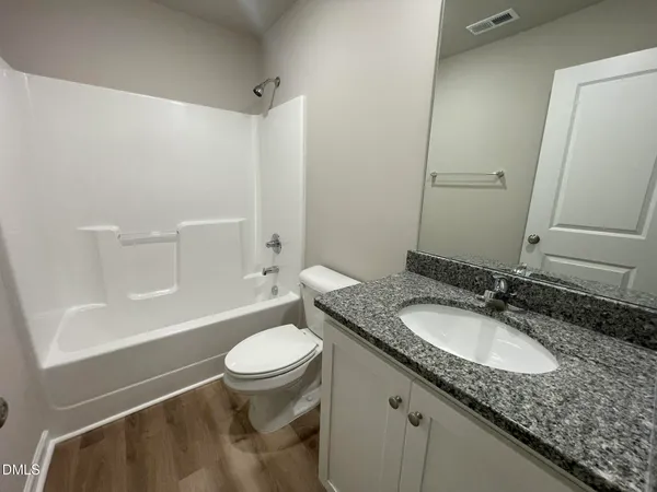 a bathroom with a granite countertop sink toilet and a mirror