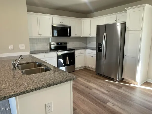 a kitchen with granite countertop a refrigerator stove and microwave