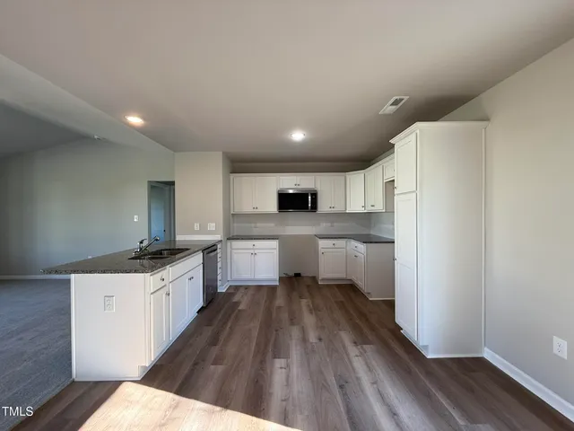 a kitchen with granite countertop a sink stove and refrigerator