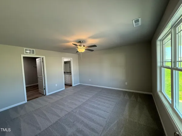 an empty room with chandelier fan and windows