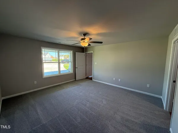 an empty room with a ceiling fan and window