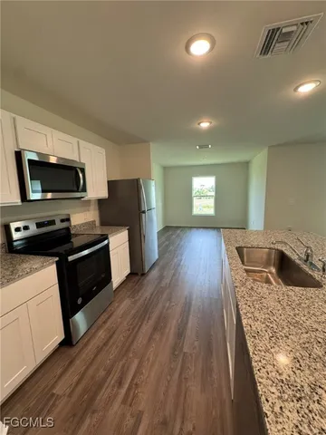a kitchen with granite countertop a refrigerator stove and sink