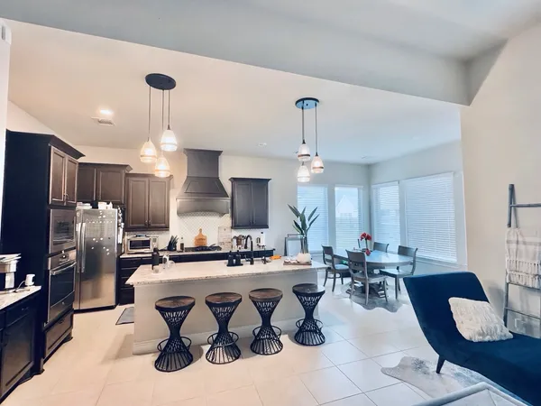 a large kitchen with a table chairs refrigerator and cabinets