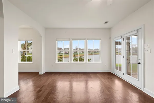 an empty room with wooden floor a ceiling fan a fireplace and windows
