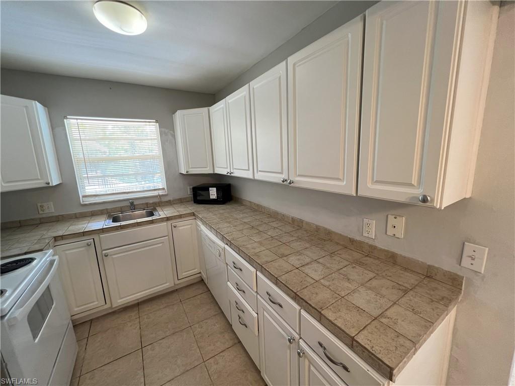 4290 Gulfstream Drive, Unit 16 Naples, FL 34112 - Photo 3 of 11 a kitchen with stainless steel appliances granite countertop a sink window and cabinets