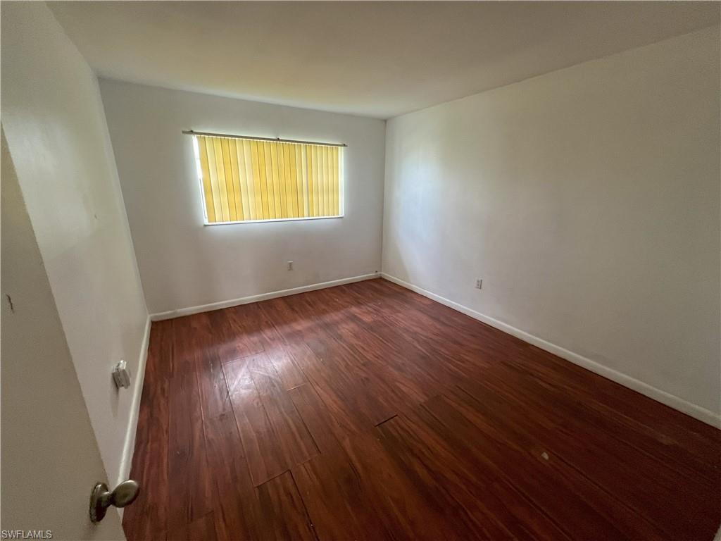 4290 Gulfstream Drive, Unit 16 Naples, FL 34112 - Photo 9 of 11 an empty room with wooden floor and windows